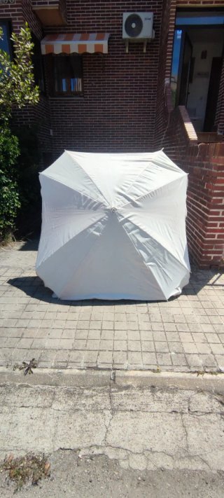 Sombrilla grande de tela beige, sin pedestal.