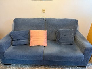 Sofá de tela azul con cojín rosa