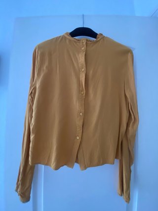 Camisa de mangas largas, mostaza abotonada detras.