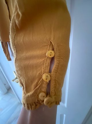 Camisa de mangas largas, mostaza abotonada detras.