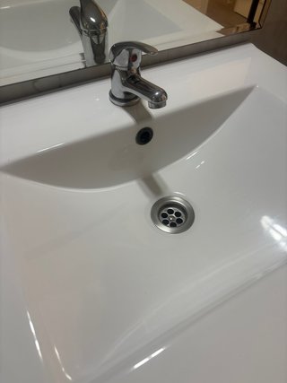 Mueble de baño blanco con lavabo y grifo