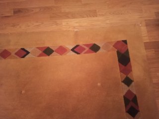 Alfombra naranja con borde geométrico