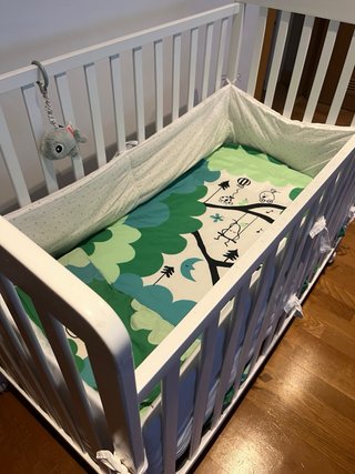 Cuna blanca con protector y ropa de cama