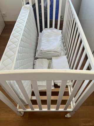 Cuna blanca con protector y ropa de cama