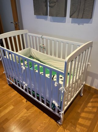 Cuna blanca con protector y ropa de cama
