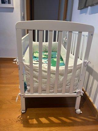 Cuna blanca con protector y ropa de cama