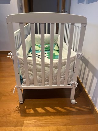 Cuna blanca con protector y ropa de cama