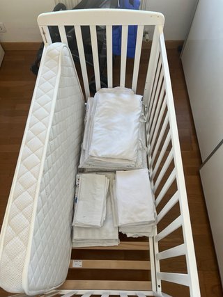 Cuna blanca con protector y ropa de cama