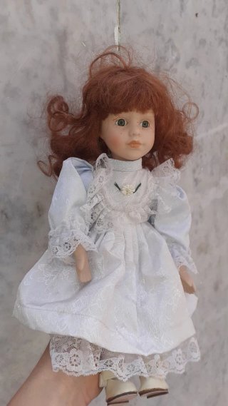 Muñeca de porcelana con vestido blanco