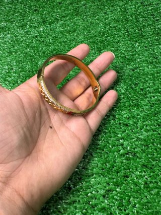 Pulsera dorada con detalles verdes y blancos