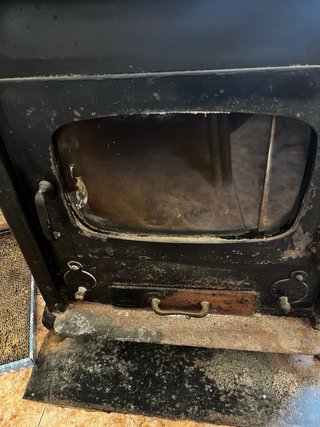 Estufa de leña negra con puerta de cristal