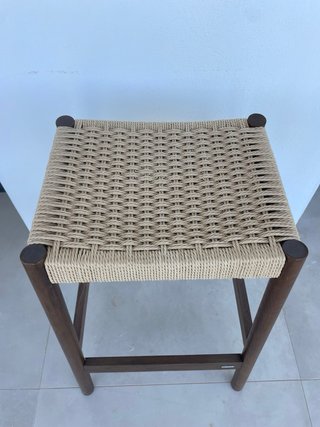 Taburete de madera con asiento de cuerda.