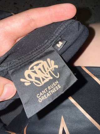 Camiseta Negra Syna con Logo Metálico