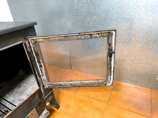 Estufa de leña negra con puerta de cristal