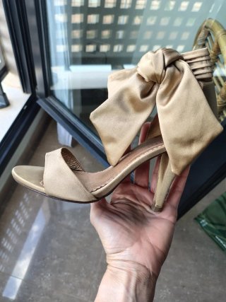 Zapatos de tacón dorados con lazo y bolso a juego.