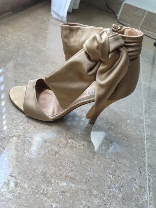 Zapatos de tacón dorados con lazo y bolso a juego.