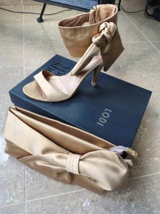 Zapatos de tacón dorados con lazo y bolso a juego.