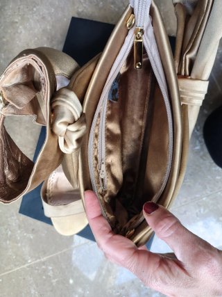 Zapatos de tacón dorados con lazo y bolso a juego.