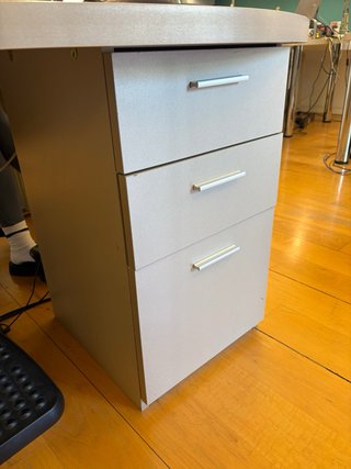 Escritorio gris en L con cajonera