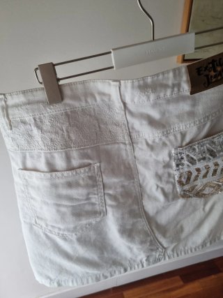 Falda corta desigual blanca con detalles dorados