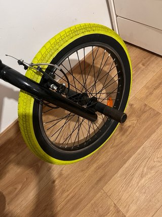 Bicicleta BMX plateada con ruedas amarillas