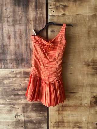Vestido naranja plisado con reflejos dorados.