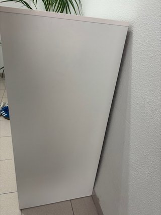 Comò bianco con maniglie nere in metallo.