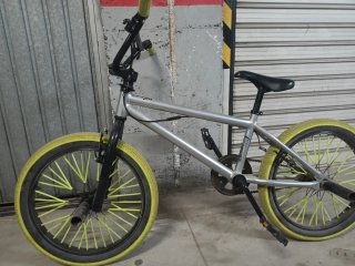 Bici BMX color gris con ruedas amarillas.