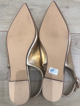 Zapatos planos dorados con punta destalonados.