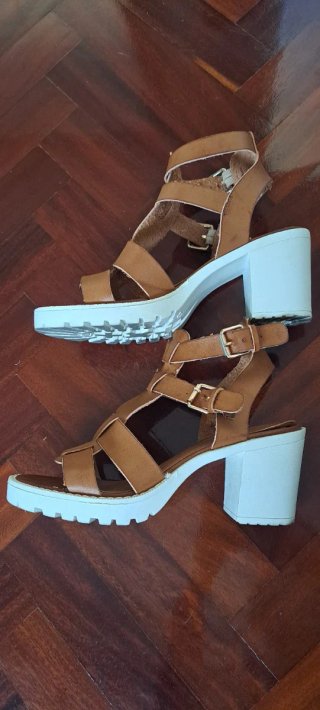 Sandalias marrón con suela blanca.