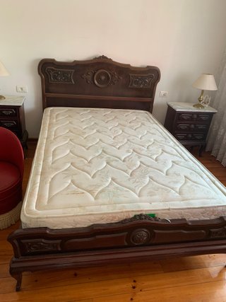 Cama de madera oscura con cabecero tallado