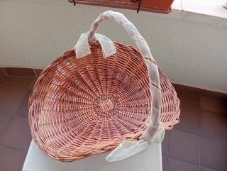 Cesta de mimbre decorada con lazo de arpillera.