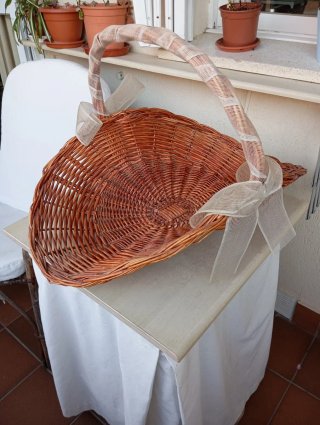 Cesta de mimbre decorada con lazo de arpillera.