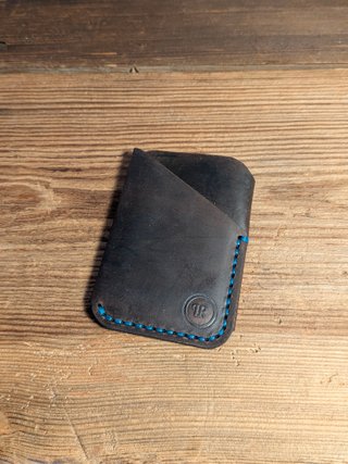 Cartera artesanal de piel marrón con costura azul