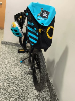 Bicicleta infantil con casco, cesta y mochila.