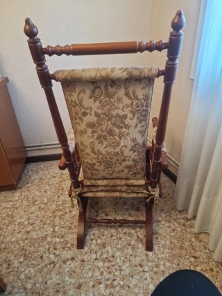 Mecedora antigua de madera y tela floral.