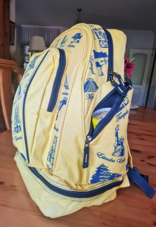 Mochila amarilla con estampados de viajes