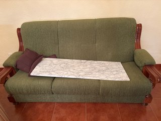 Sofá de tela verde con detalles de madera