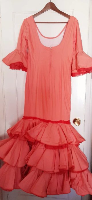 Traje de flamenca salmón con varios complementos.