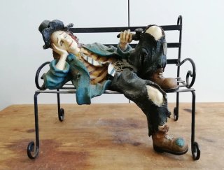 Figura payaso durmiendo en banco
