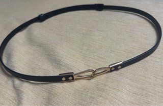 Cinturón negro fino con hebilla dorada