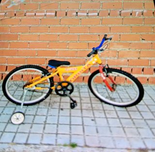 Bicicleta infantil amarilla con ruedines