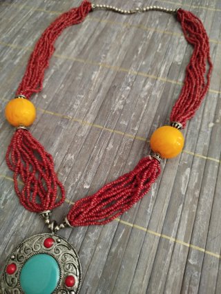 Collar de cuentas burdeos con colgante turquesa.