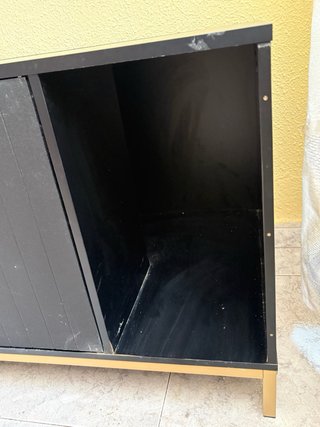 Mueble arenero con patas y pomos en dorado.