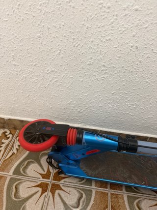 Patinete azul con ruedas rojas