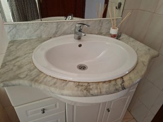 Mueble de lavabo, encimera de mármol y espejo.