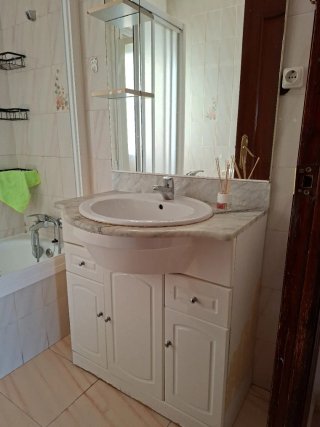 Mueble de lavabo, encimera de mármol y espejo.