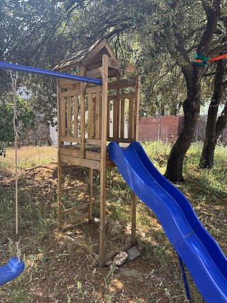 Parque infantil exterior con columpios y tobogán
