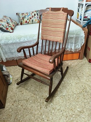 Mecedora antigua de madera con cojines.