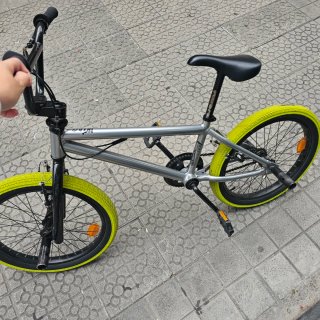 Bicicleta BMX plateada con ruedas verdes